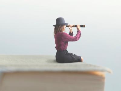 Woman sitting on a book looking through a monocular