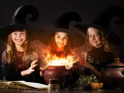 Three child witches around a cauldron with golden swirls coming off of it.