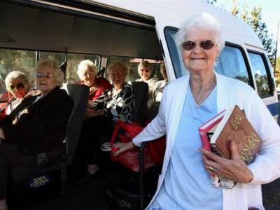 Senior holding books while standing next to a bus