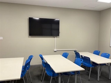 Desks with chairs and a TV mounted to the wall 1