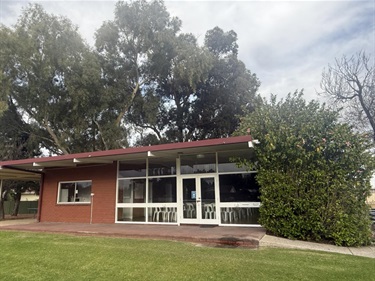 Front of Memorial Park Hall showing white framed windows overlooking a verandah and grassed area