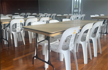 Timber floor with rectangular tables and white plastic chairs