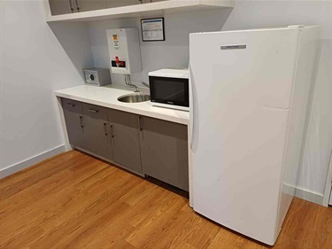Kitchenette with base cupboards, microwave and fridge