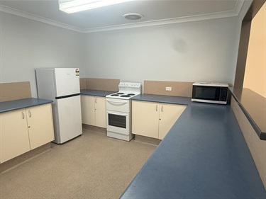 Inside kitchen at Southern River Hall with blue laminate benchtops cream cabinets fridge stove and microwave