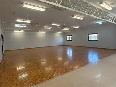 Inside Southern River Hall with carpeted area in foreground timber parquetry flooring in main hall section and fluorescent lighting