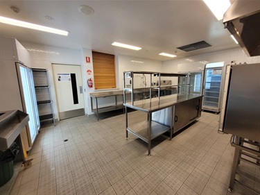 Commercial kitchen with tiled floor and stainless steel benches