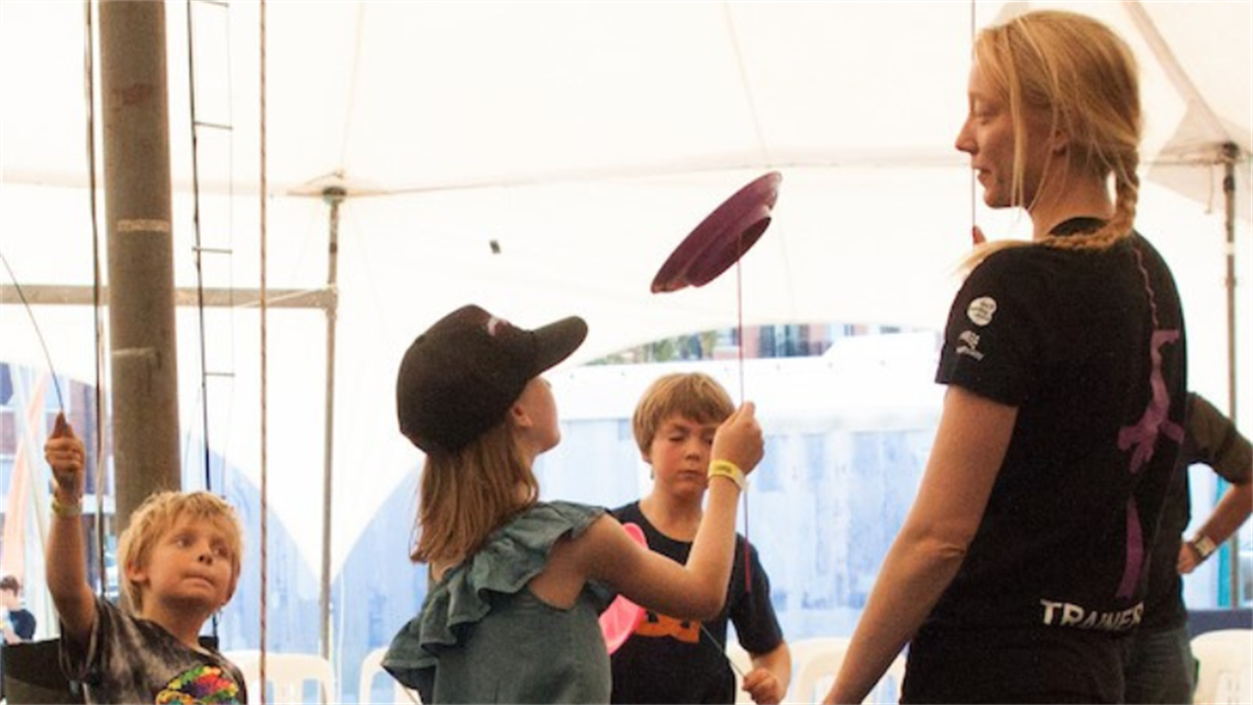 Circus WA trainer showing children how to spin plates.