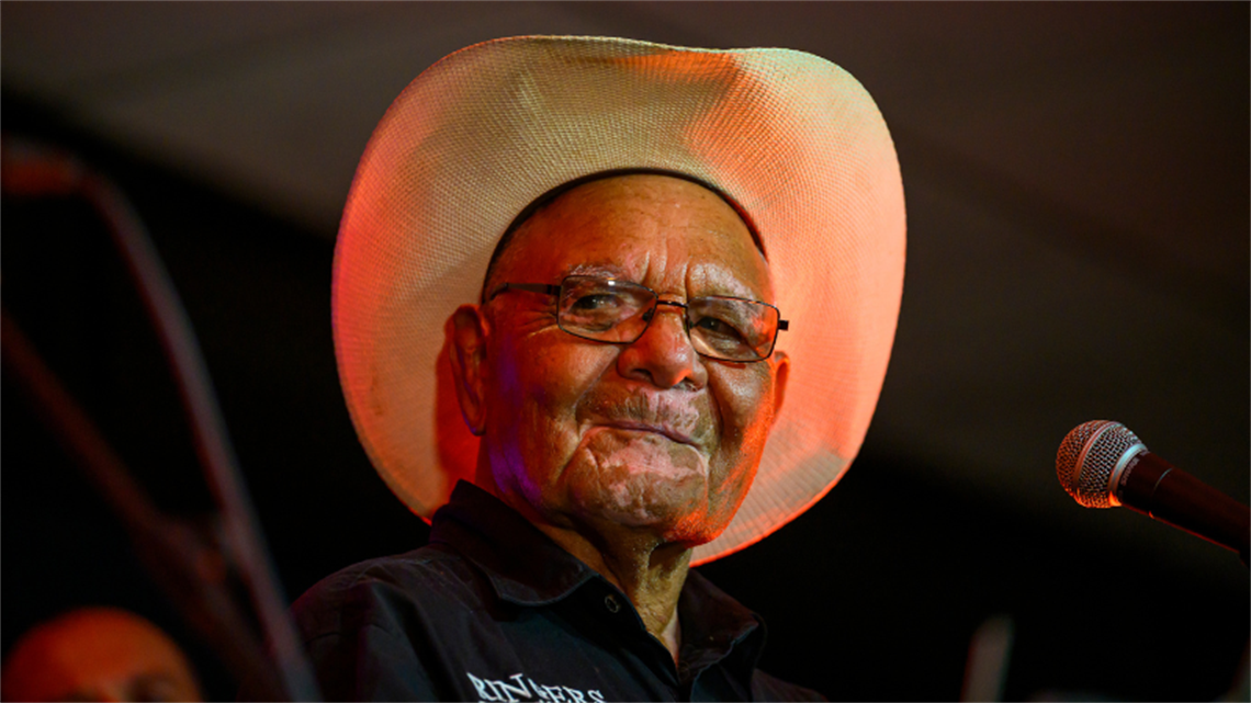 Close up photo of Peter Salmon's face, as he grins onstage.
