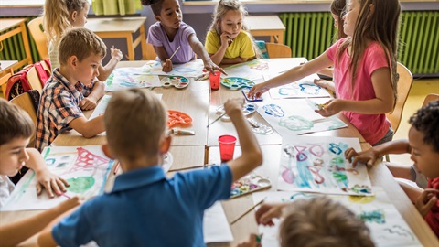 A group of kids around a large table covered with art supplies.jpg
