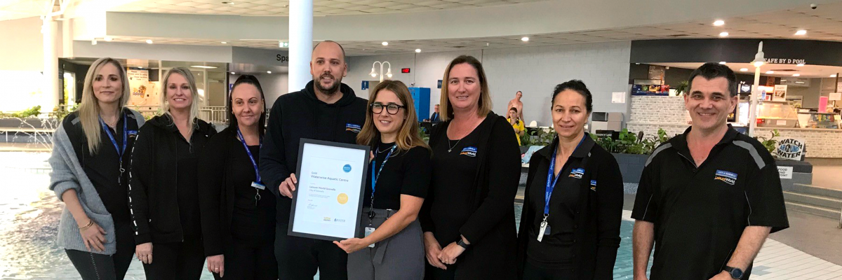 Water Corporation Customer & Stakeholder Specialist Louise Vaughan with Acting Leisure World Coordinator Mark Sinfield, with the award for being a Gold Waterwise Aquatic Centre, accompanied by Leisure World staff.