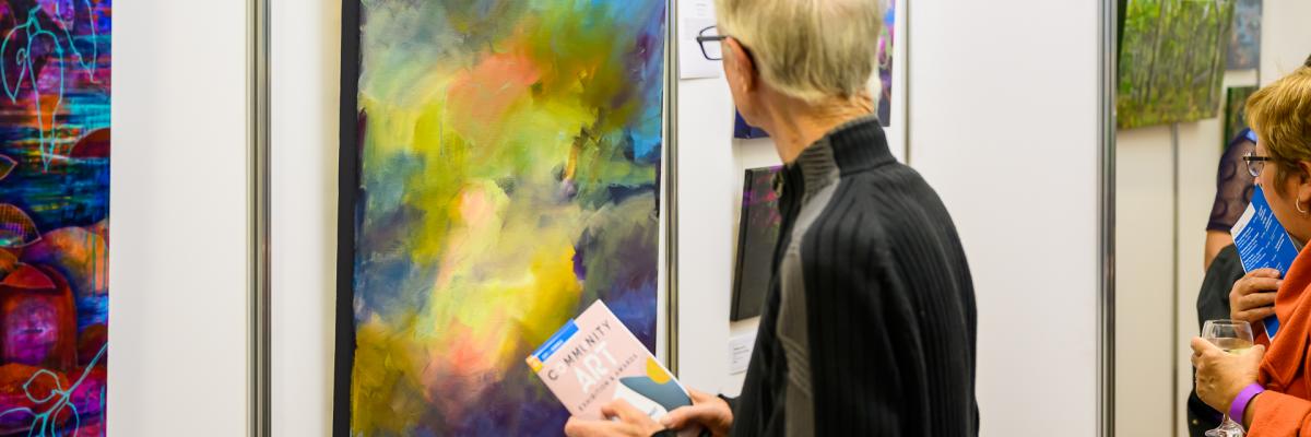 Man viewing colourful artwork at the 2022 Community Art Exhibition and Awards