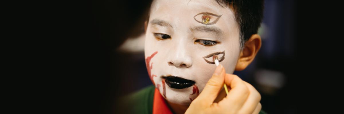 young boy having his face painted with Opera style makeup
