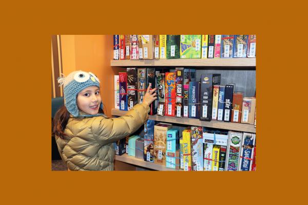 Girl choosing from a shelf of board games