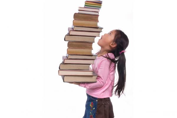 girl holding a tall stack of books