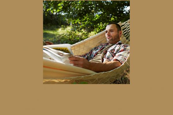 Man laying in a hammock reading a magazine
