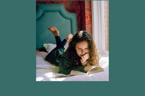 Girl laying on her bed reading a book