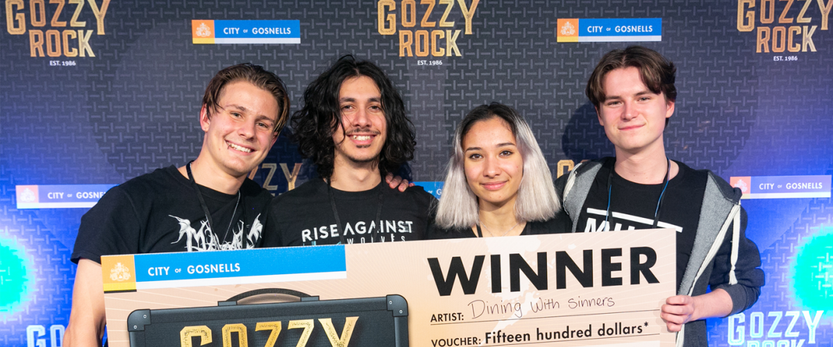 4 young musicans holding an oversized novelty check given to them for winning the 2021 musical talent show: Gozzy Rock