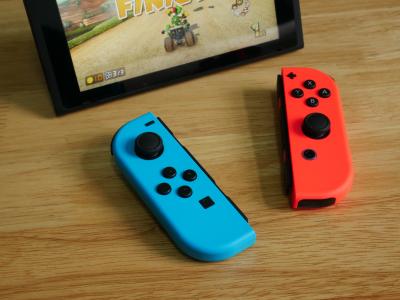 Red & blue Nintendo switch controllers on a table in front of a tablet screen