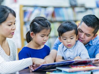 Two young children reading with their parents at the Library
