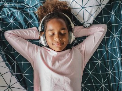 Young girl smiles with eyes closed and headphones on