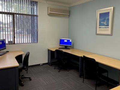 small room with computers and office chairs