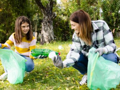 Two women collect rubbish at an park 