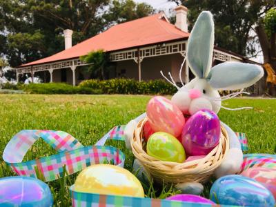 Toy rabbit holding a basket of colourful eggs in front of the City of Gosnells Museum homestead.