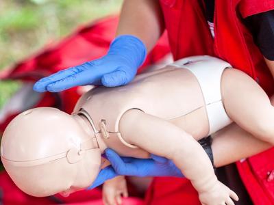 First Aid demonstrator holding child resuscitation dummy