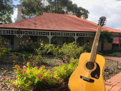 An acoustic guitar sits in front of the Museum homestead and garden.
