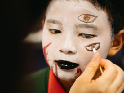 young boy having his face painted with Opera style makeup
