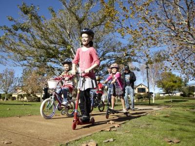Children riding scooters and bicycles on a path