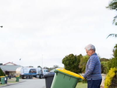 Man pushing recycling bin to the kerb for collection